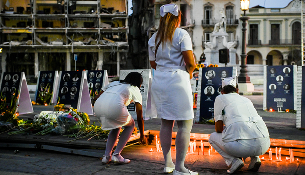 Enfermeras encienden velas durante la vigilia por las víctimas del accidente del Hotel Saratoga en La Habana.AFP