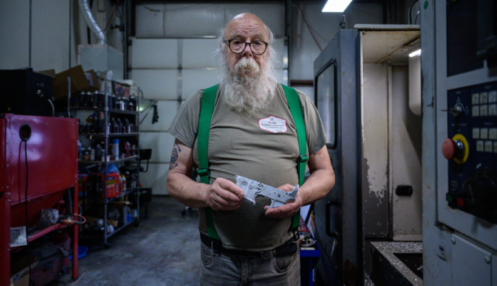 Paul Marquis sostiene un recibidor de rifle en su pequeño taller, donde vende y renta armas y sus piezas, en Goffstown, New Hampshire. /AFP.