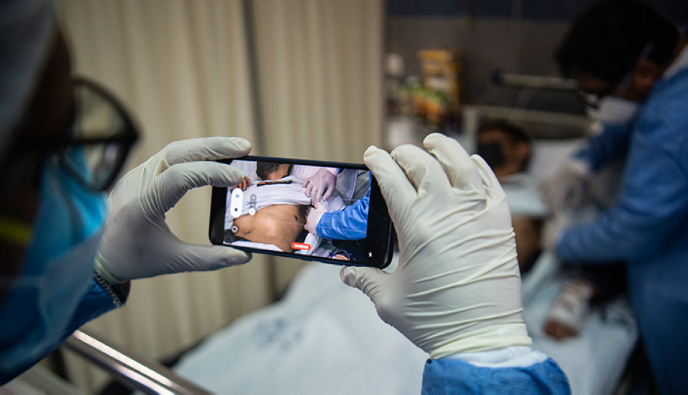 Un médico revisa a un paciente con llagas causadas por una infección de viruela del mono mientras otro toma una fotografía en Lima, Perú.AFP