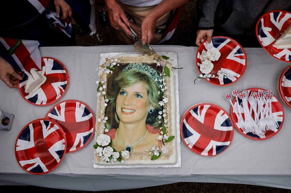 Visitantes parten un pastel en honor a la princesa Diana frente al palacio Kensington en Londres / AFP