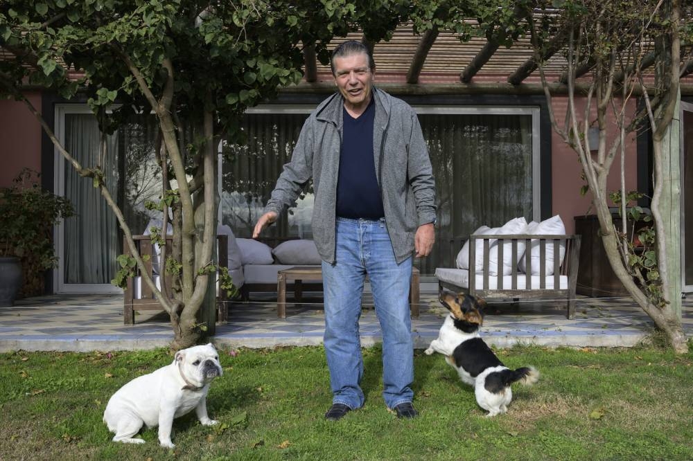 Carlos Páez, uno de los 16 sobrevivientes de un accidente aéreo en los Andes chilenos en 1972 y que permaneció perdido en las montañas durante 72 días, posa con sus perros en su casa en Viñedos de la Tahona, departamento de Canelones, Uruguay.