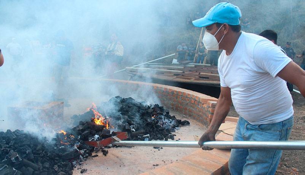 Varios hombres trabajan en encender la hornilla para la pupusa gigante, utilizando cerca de 90 libras de carbón. / Gabriel Aquino