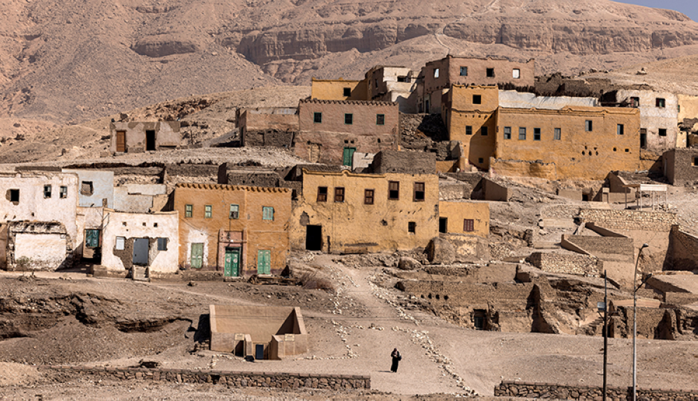 una mujer se aleja de los viejos edificios de adobe en la parte parcialmente evacuada del pueblo de al-Qurna (Gurna), en la orilla oeste del río Nilo frente a Egipto.AFP