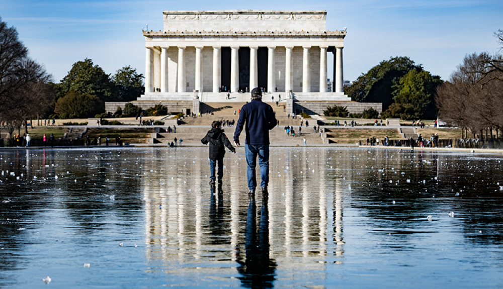 Un hombre y un niño caminan por la piscina reflectante congelada hacia el Monumento a Lincoln en el National Mall en Washington, DC.AFP