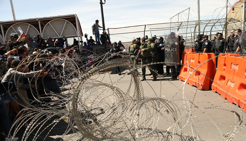 Migrants received by US security forces at barricades and barbed wire.AFP