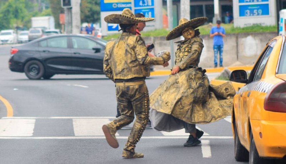The duo uses traffic lights or moments of movement to dance in front of the Salvadorans. 