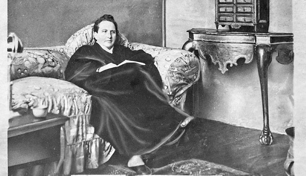 A photograph of Gertrude Stein in her home in Paris, 1930, wearing the famous portrait.