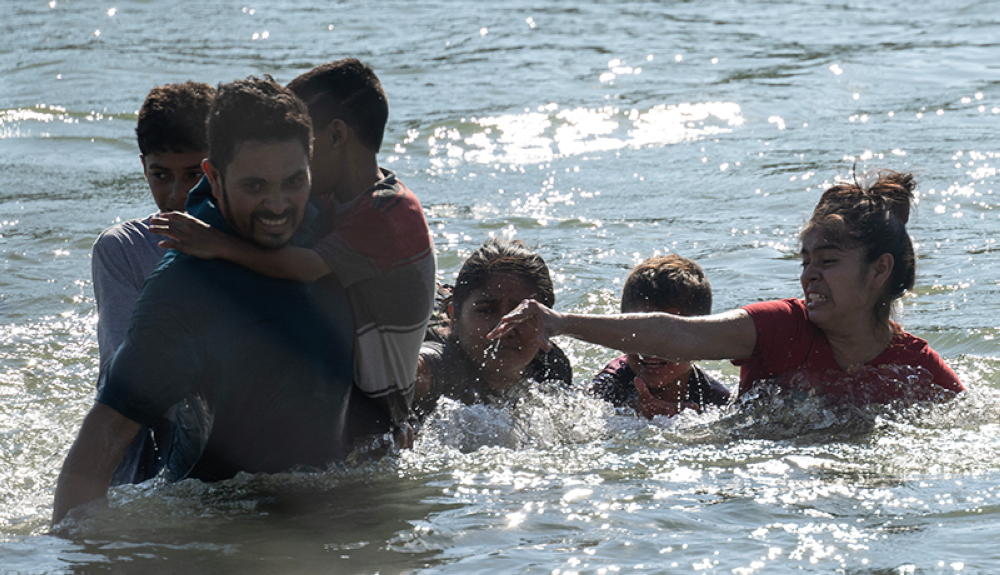 Una familia se aferra mientras intenta navegar por las rápidas corrientes del río Grande mientras cruzan la frontera entre Estados Unidos y México hacia Eagle Pass.AFP