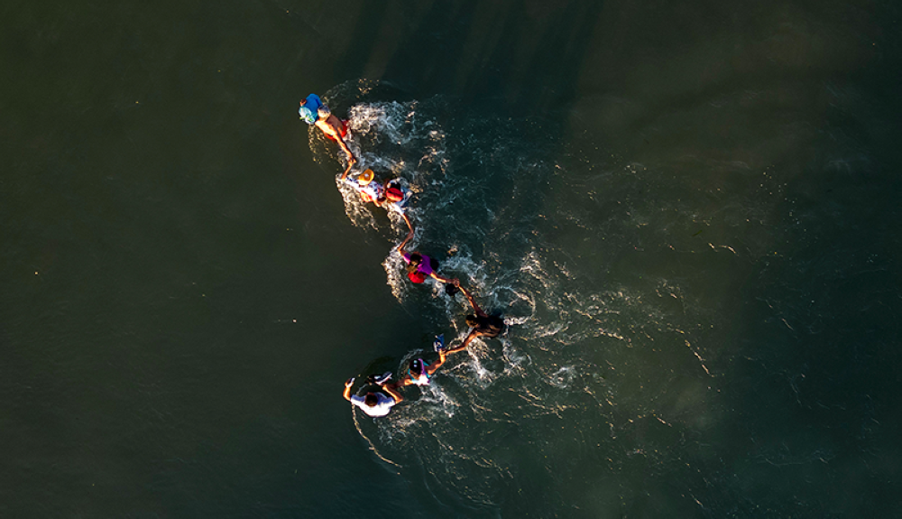 Esta fotografía aérea muestra a una familia aferrándose mientras intentan navegar por las rápidas corrientes del río Grande entre Estados Unidos y México hacia Eagle Pass, Texas.AFP