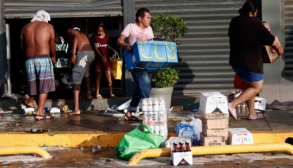 La gente recoge comestibles en un supermercado saqueado después del paso del huracán Otis en Acapulco, estado de Guerrero, México.AFP