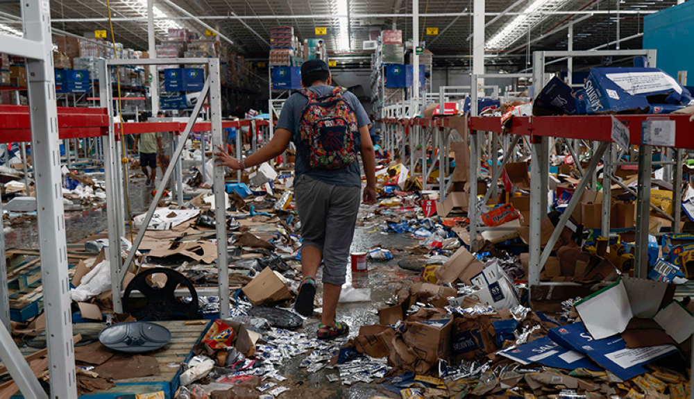 Un hombre camina sobre un supermercado saqueado después del paso del huracán Otis en Acapulco, estado de Guerrero, México.AFP