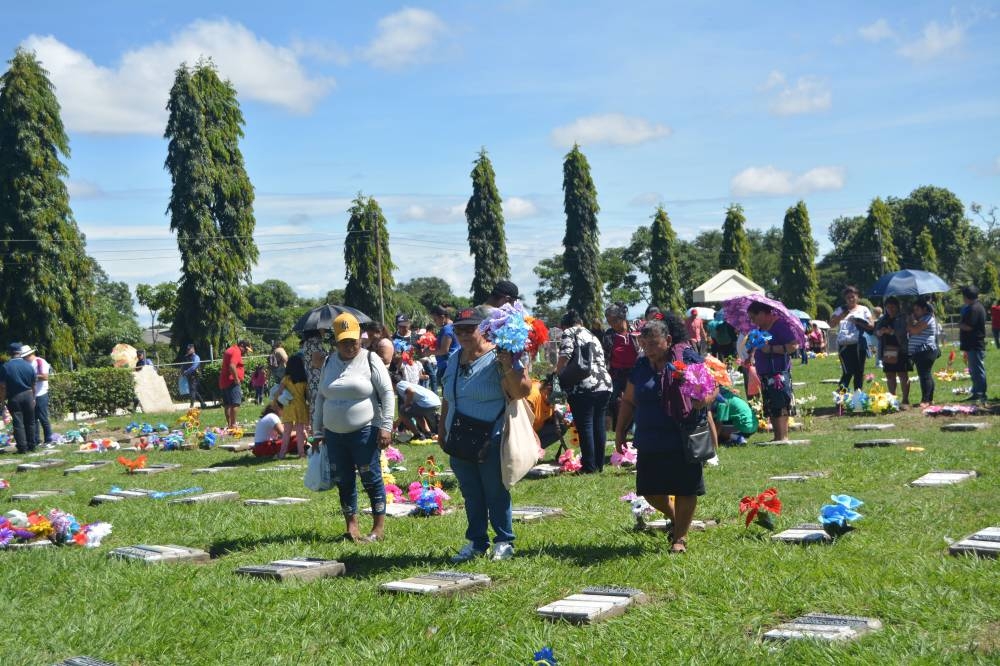 Salvadoreños asisten al cementerio La Bermeja para honrar a sus seres queridos llevándoles flores.