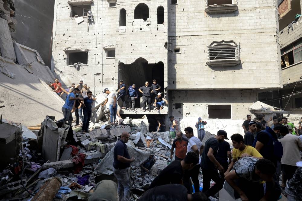 Los palestinos buscan supervivientes entre los escombros de un edificio alcanzado por un ataque aéreo israelí en Khan Yunis, en el sur de la Franja de Gaza. Miles de civiles, tanto palestinos como israelíes, han muerto desde el 7 de octubre de 2023, después de que Hamas palestino Militantes con base en la Franja de Gaza.