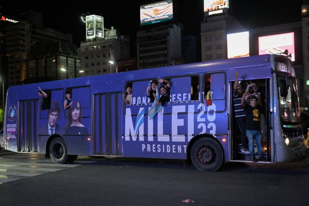 Los partidarios del candidato presidencial argentino por la alianza La Libertad Avanza, Javier Milei, celebran su victoria en la segunda vuelta de las elecciones presidenciales a bordo de un autobús en el Obelisco de Buenos Aires. AFP.  