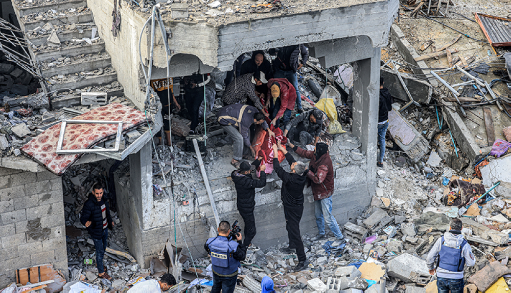 Hombres recuperan el cuerpo de una víctima muerta tras un ataque israelí nocturno en el campo de refugiados de al-Maghazi.AFP