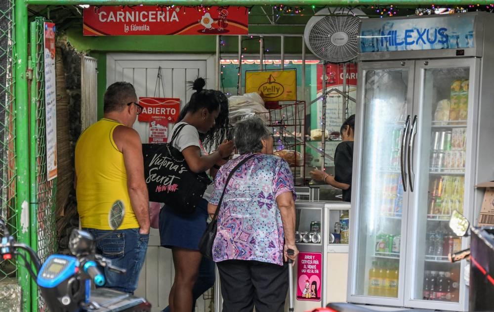 La gente mira los precios de los alimentos en un negocio privado en La Habana el 8 de marzo de 2024. (Foto de YAMIL LAGE / AFP)