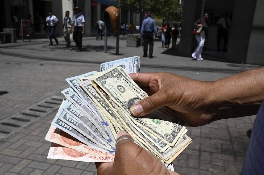 Un cambista con dólares y lempiras (la moneda hondureña) en las calles de Tegucigalpa, Honduras./AFP 