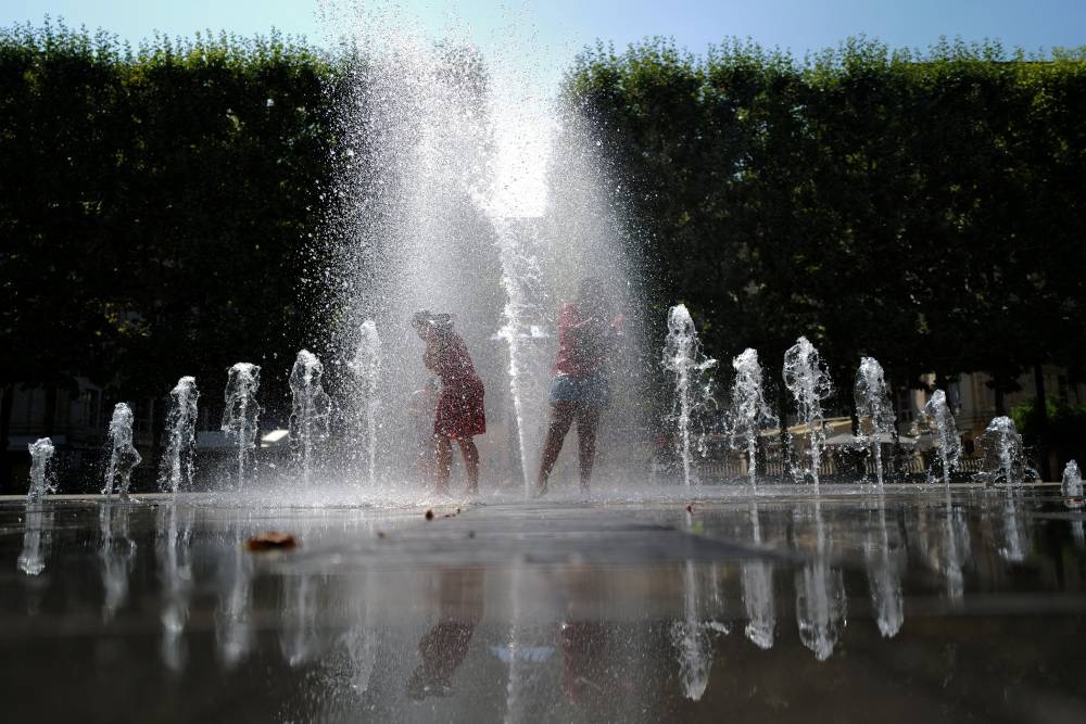 Dos niños se refrescan en medio de las altas temperaturas en Francia./AFP
