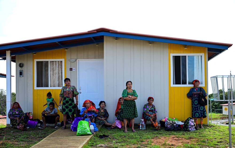 Los indígenas Gunas esperan afuera de sus nuevos hogares en Nuevo Carti, Comarca Guna Yala, en la costa caribeña de Panamá continental, el 29 de mayo de 2024. - Las autoridades panameñas entregarán las llaves de sus nuevos hogares en el continente a unas 300 familias de Gardi. Foto de MARTIN BERNETTI / AFP