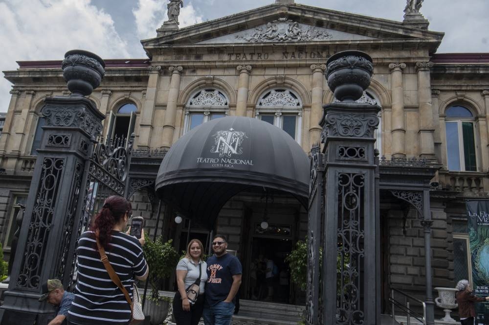 Turistas posan para una instantánea frente al Teatro Nacional en San José, Costa Rica. /AFP,image_description: