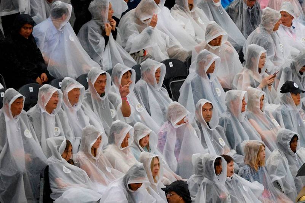 Las capuchas transparentes también tuvieron foco en una ceremonia marcada por la lluvia. / AFP