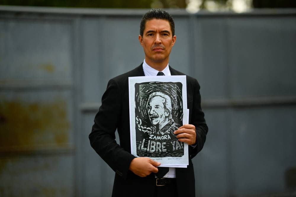 José, hijo del periodista guatemalteco José Rubén Zamora, tiene un dibujo de su padre cuando sale de la prisión para hombres Mariscal Zabala en la ciudad de Guatemala el 30 de julio de 2024. Romeu pidió el 30 de julio de 2024 la liberación del periodista José Rubén Zamora, después de visitar en una cárcel guatemalteca. (Foto de JOHAN ORDÓNEZ/AFP)