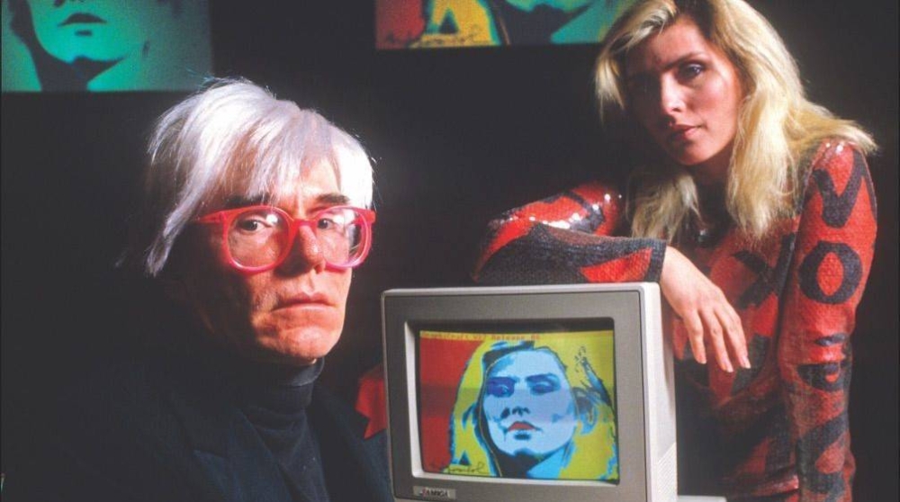 Andy Warhol y Debbie Harry durante la creación del retrato con una computadora Amiga 1000.,image_description: