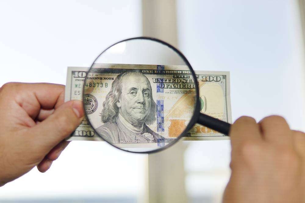 El Banco Central señala que los billetes falsos más comunes son de 10 y 20. /DEM,image_description:two dollar bill and magnifying glass isolated on white