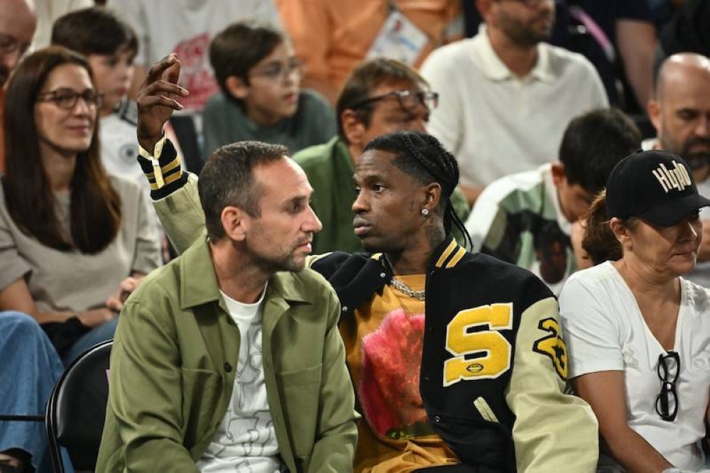 Travis Scott, al centro, en una semifinal de basquetbol durante los Juegos Olímpicos. / AFP.,image_description: