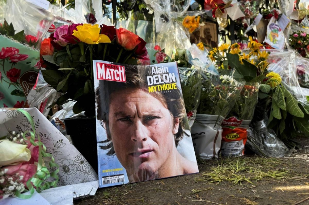 Alain Delon en sus años mozos en una portada de revista colocada frente a su hogar de Douchy, Francia. / Photo by Tom MASSON / AFP,image_description: