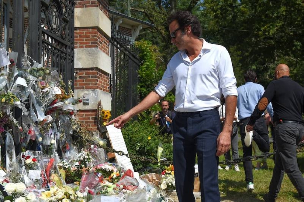 El actor francés Anthony Delon mira los ramos de flores y los mensajes que se exhiben en la puerta de entrada de la propiedad de su padre antes de un funeral privado del fallecido actor francés Alain Delon  en el centro de Francia./ AFP,image_description: