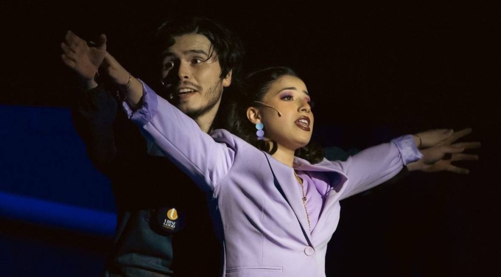 Gabriel Pinto y Adri Mojica en una icónica escena de la obra musical Urinetown, de Black Coyote, en El Salvador.,image_description: