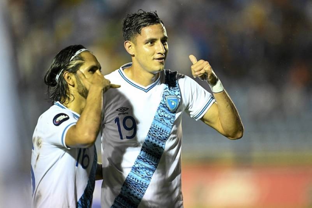 El delantero guatemalteco, José Martínez der., celebra con su compañero de equipo, el defensa José Morales, después de anotar durante el partido de fútbol de la fase de grupos de la Liga de Naciones de la Concacaf entre Guatemala y Martinica en el estadio Doroteo Gamuch Flores en la Ciudad de Guatemala.AFP,image_description: