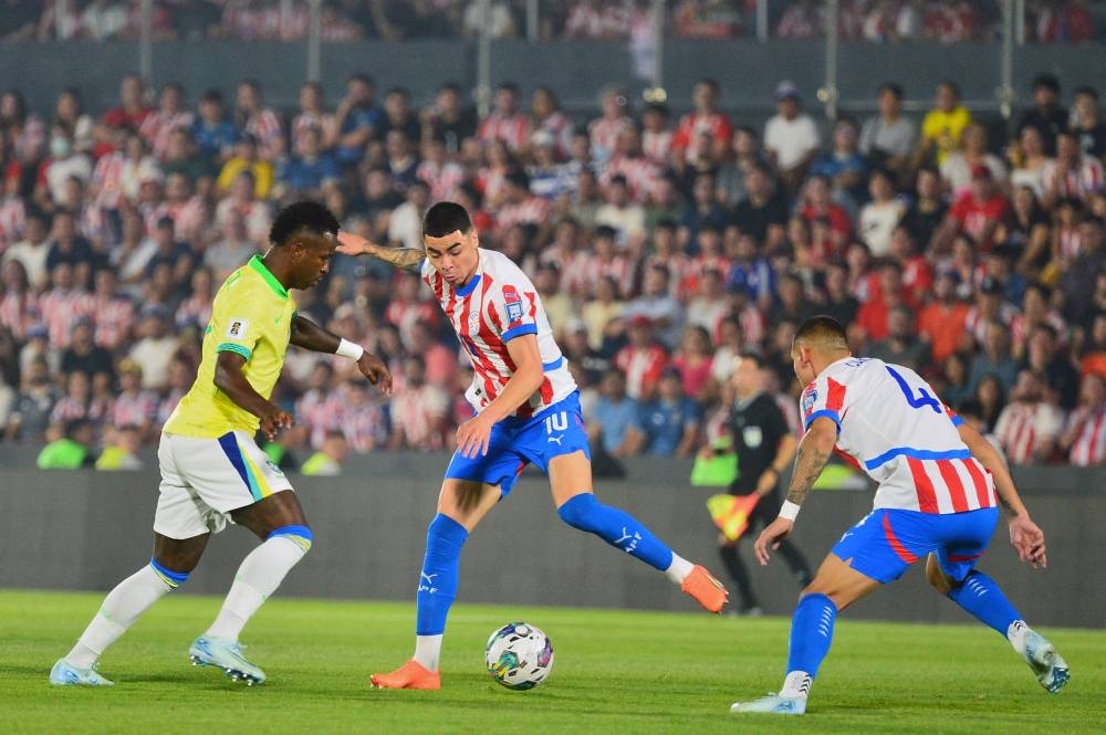 Vinicius Jr observa al paraguayo Miguel Almirón en el partido jugado en Asunción. / AFP,image_description: