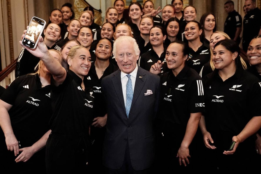 El rey Carlos III posa para una selfie con miembros del equipo de rugby Black Ferns de Nueva Zelanda, en el Palacio de Buckingham este 11 de septiembre. Photo by Aaron Chown / POOL / AFP,image_description: