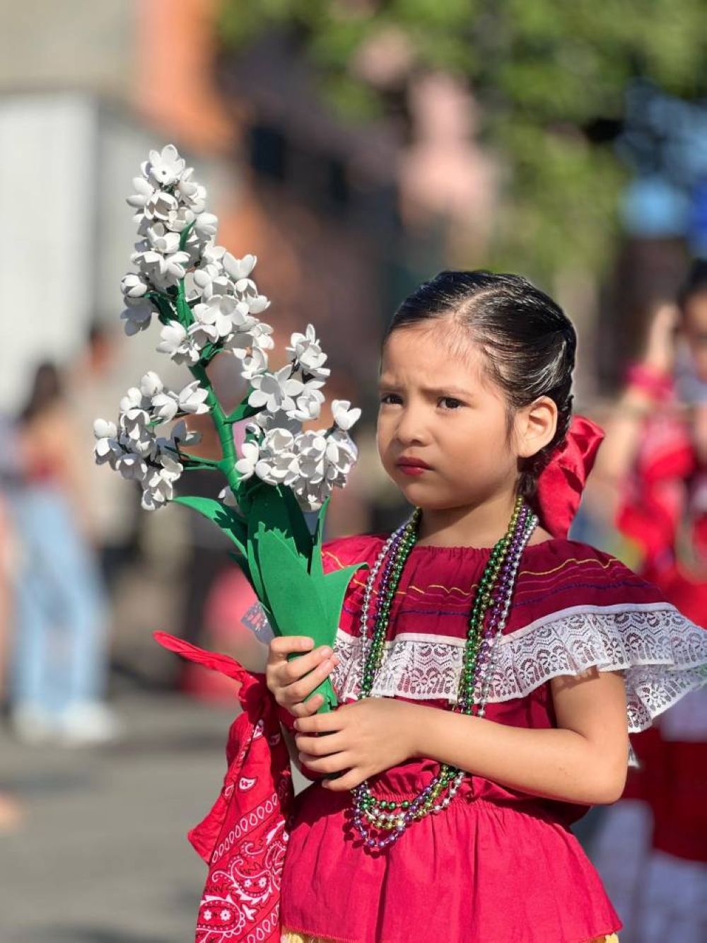 Niña estudiante de Antiguo Cuscatlán porta un traje típico y una representación de la flor nacional. / @AlcaldiaAntiguo
