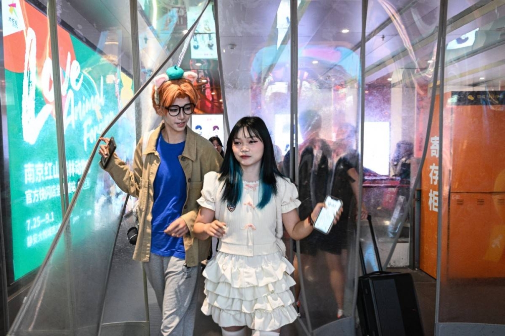 La cosplayer Xu Yunting interpreta a Jesse, un personaje masculino del videojuego Light and Night, junto a Feng Xinyu, de compras. Photo by Hector RETAMAL / AFP,image_description: