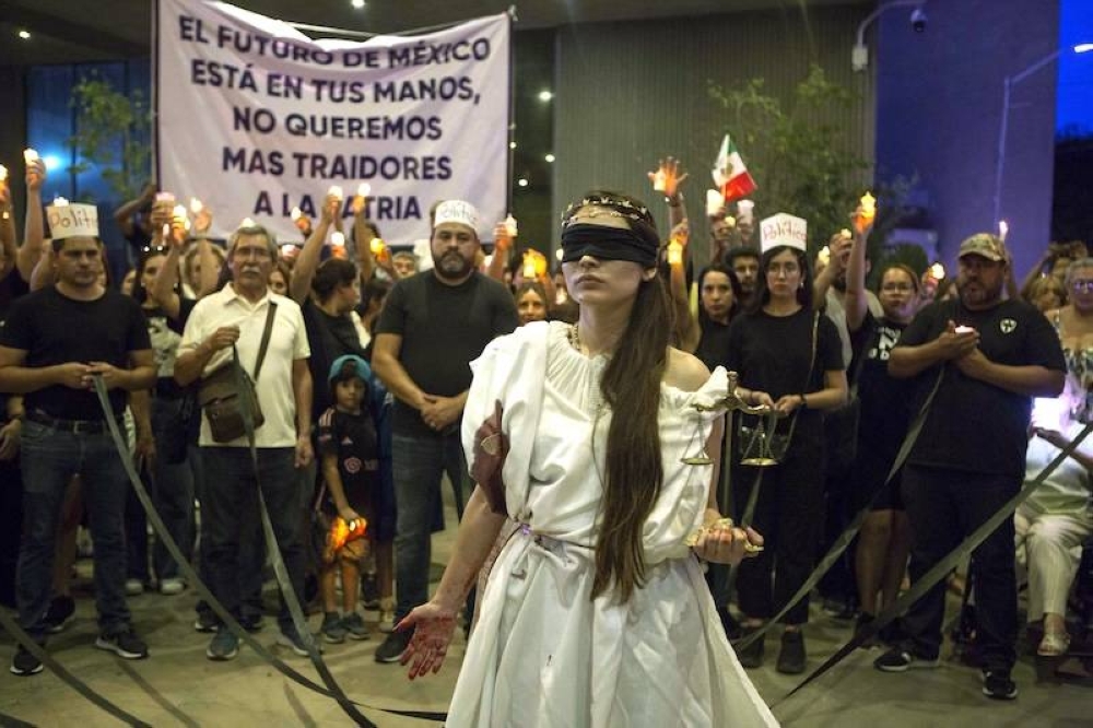 Una manifestante vestida como Themis participa en una protesta contra la reforma judicial afuera del Congreso del Estado de Nuevo León en Monterrey, México. El presidente mexicano, Andrés Manuel López Obrador, anunció que su controvertida reforma judicial, que prevé la elección de todos los jueces por voto popular, ya fue promulgada después de obtener el apoyo de 18 congresos estatales./ AFP,image_description: