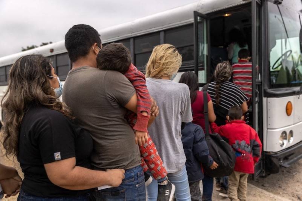 Familias centroamericanas abordan un autobús de la Oficina de Aduanas y Protección Fronteriza de EE. UU. para ser transportadas a un centro de procesamiento de inmigrantes, en La Joya, Texas. / AFP.,image_description: