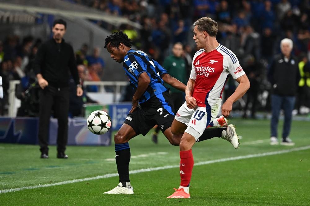 El colombiano Juan Cuadrado domina el balón ante la mirada de Leandro Trossard, del Arsenal. / AFP,image_description: