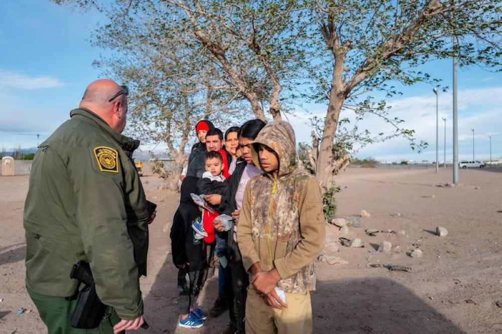 Un grupo de migrantes esperan a ser procesados luego de cruzar el río Grande el 2 de abril de 2024, en el El Paso, Texas. / AFP.,image_description: