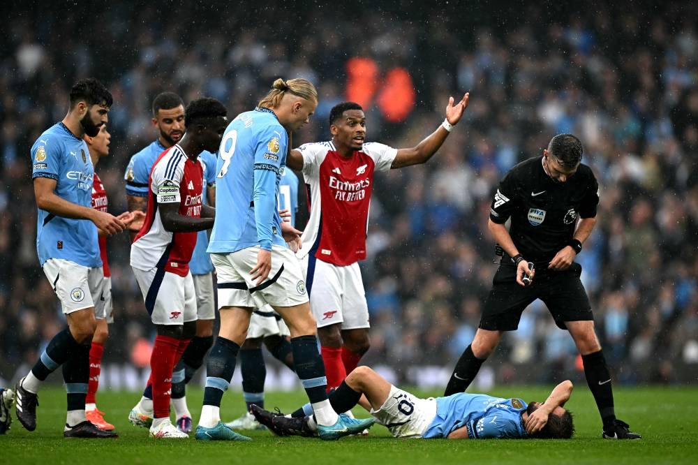 Bernardo Silva está en suelo en la jugada que terminó con la expulsión de  Leandro Trossard. / AFP,image_description: