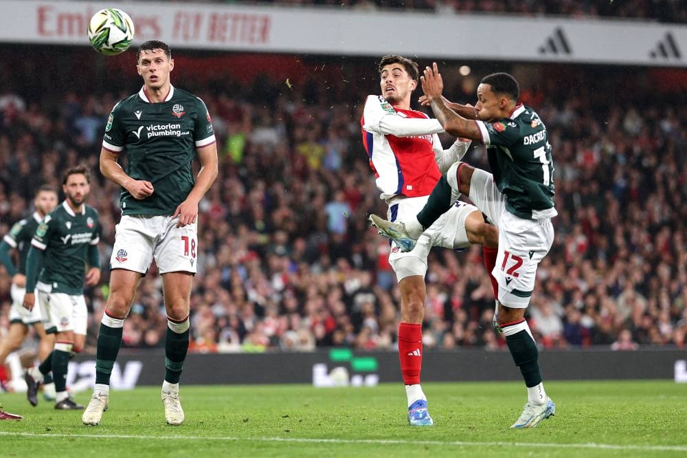 Kai Havertz, delantero del Arsenal, en plena puja por el balón con dos jugadores del Bolton. / AFP,image_description: