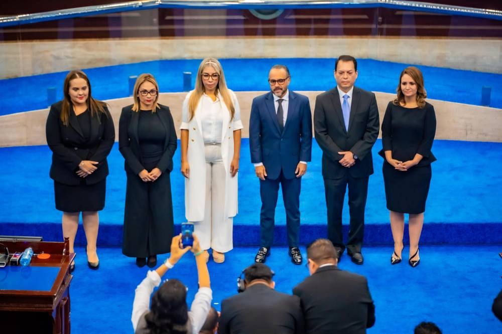 La nueva presidenta del TSE, Roxana Soriano de blanco, junto al presidente de la Asamblea Legislativa, Ernesto Castro, y magistrados propietarios juramentados. / Asamblea Legislativa.,image_description: