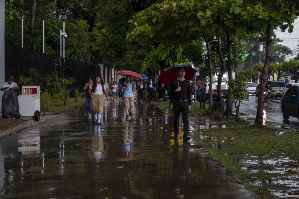 Un grupo de estudiantes camina bajo la lluvia de esta semana. / Lisbeth Ayala.,image_description: