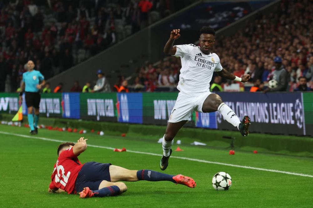 Vinicius Junior se anticipa al cierre del defensa Thomas Meunier, del Lille. / AFP,image_description: