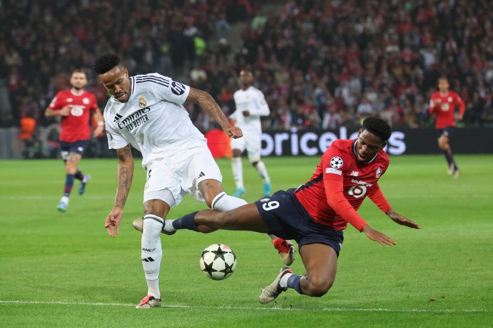 El defensor brasileño del Real Madrid 03 Eder Militao y el delantero canadiense del Lille 09 Jonathan David durante el partido de fútbol de la Liga de Campeones de la UEFA entre Lille LOSC y Real Madrid en el estadio Pierre Mauroy. /AFP,image_description: