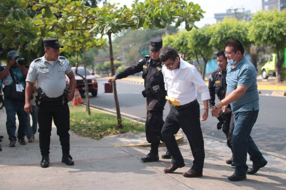 Los acusados de Santa Marta siendo llevados al edificio de Cámaras de San Salvador para la audiencia preliminar. La Policía instaló un cordón de seguridad de la Unidad de Mantenimiento del Orden, frente a la concentración de la comunidad Santa Marta. / Lisbeth Ayala.,image_description: