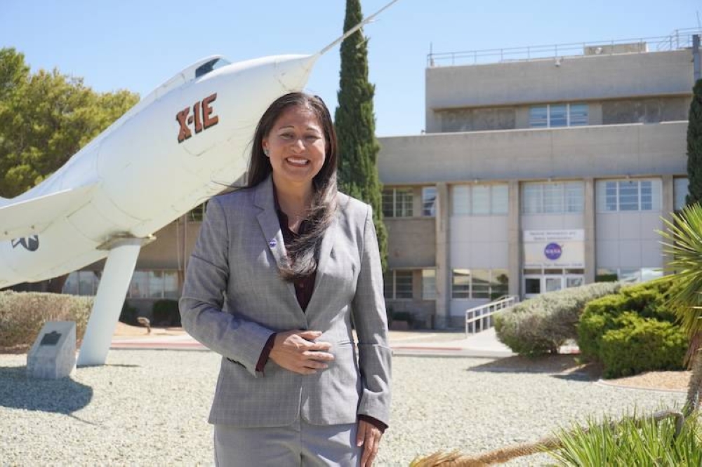 La gerente de proyectos de la NASA Patricia Ortiz se muestra delante del avión de investigación X1E en el Centro de Investigación de Vuelo Armstrong de la NASA en Edwards, California.n,image_description: