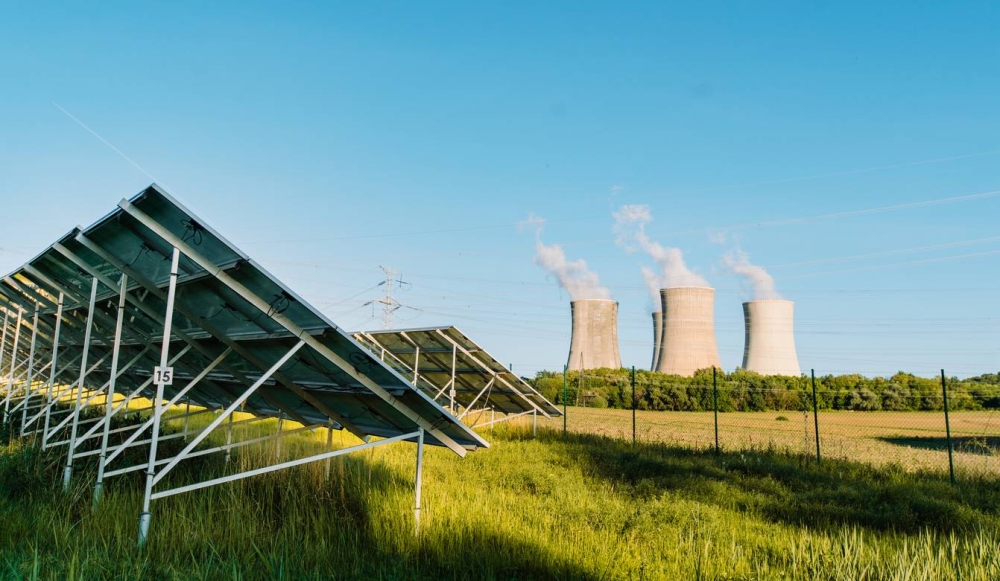 Parque solar fotovoltaico y planta de energía nuclear con torres de refrigeración al fondo. / Imagen ilustrativa.,image_description: